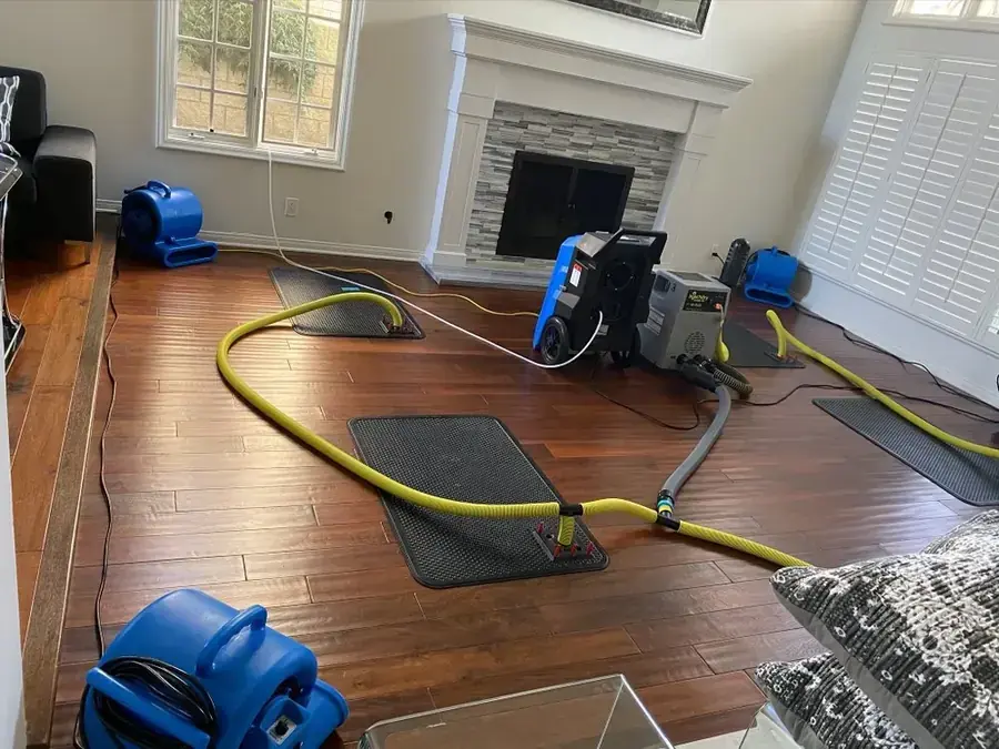 A technician extracting standing water from a hardwood floor in a Southwest Fort Worth home